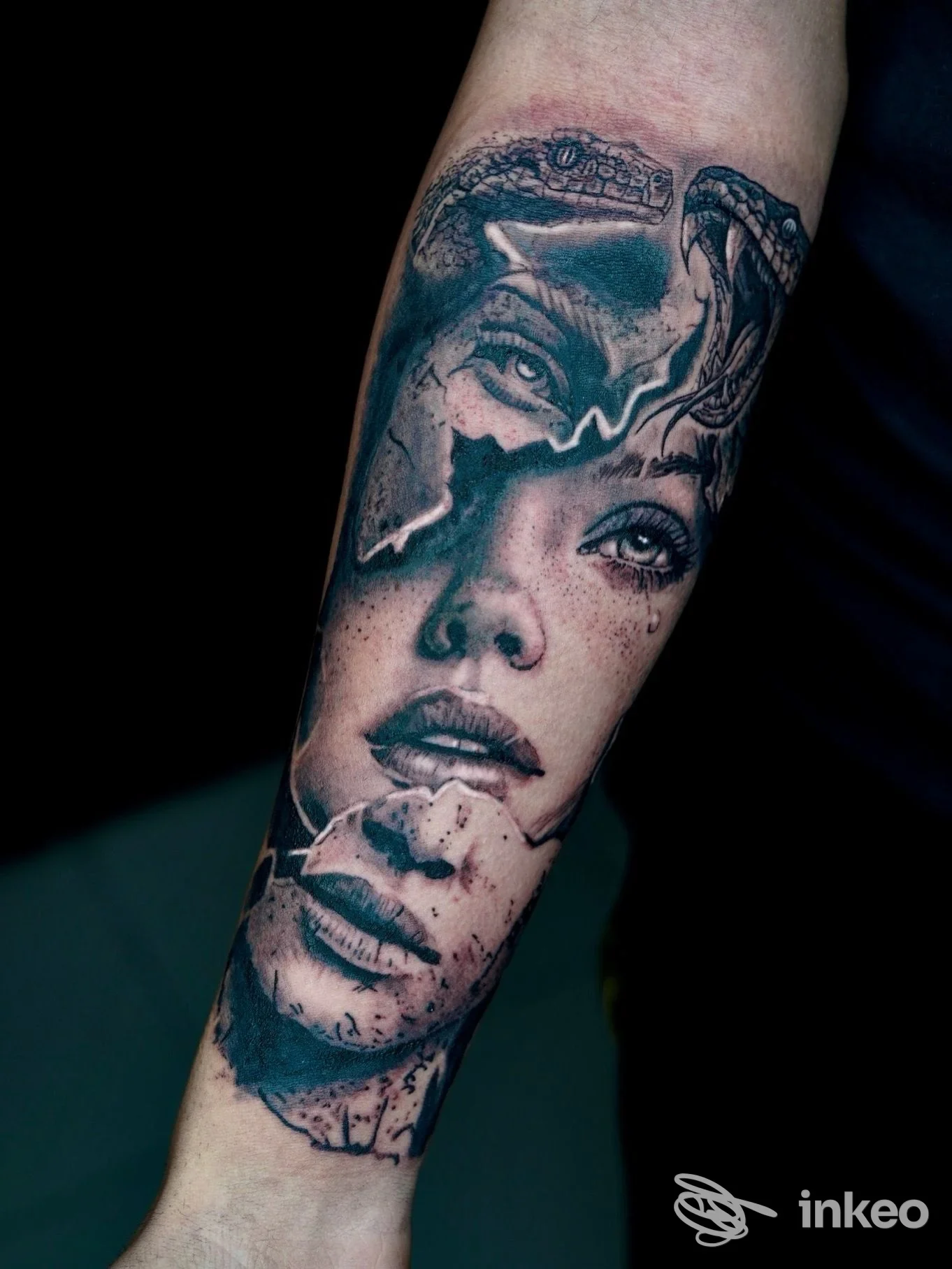 Tattoo realistico in bianco e nero su avambraccio sinistro: ritratto di donna con dettagli fini, sfumature e accenti blu, senza elementi promozionali visibili.
