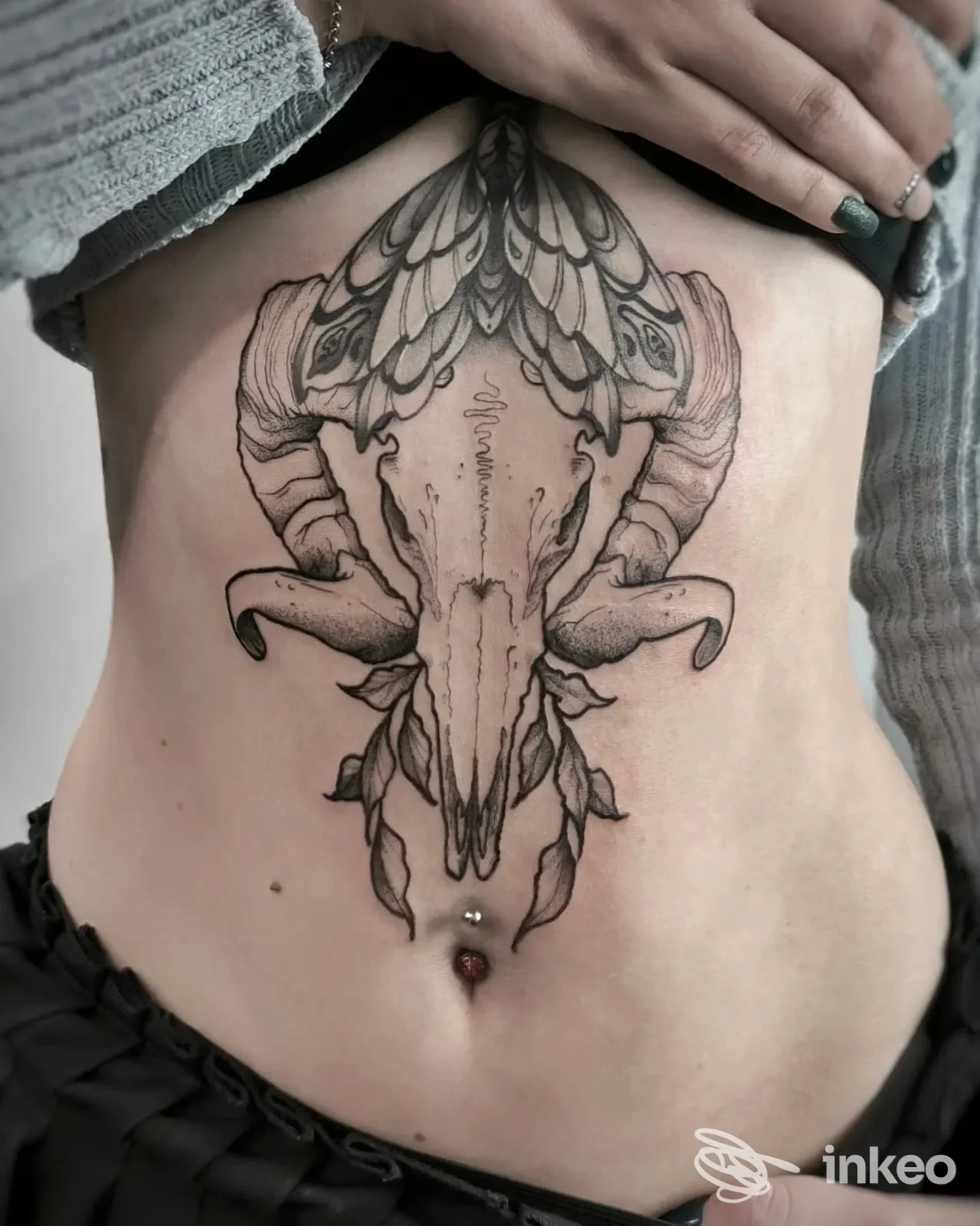 Tattoo sul ventre raffigurante una testa di bestia con corna, inciso sulla pelle, senza volto visibile. Studio Tombstones Tattoo Studio.