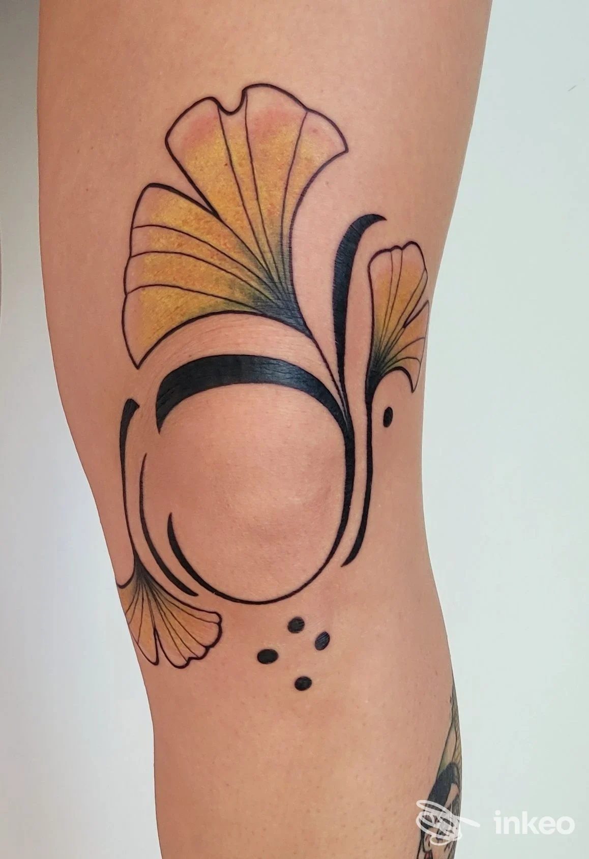 Tattoo stilizzato su braccio con motivi floreali colorati e linee nere, visibile in primo piano.