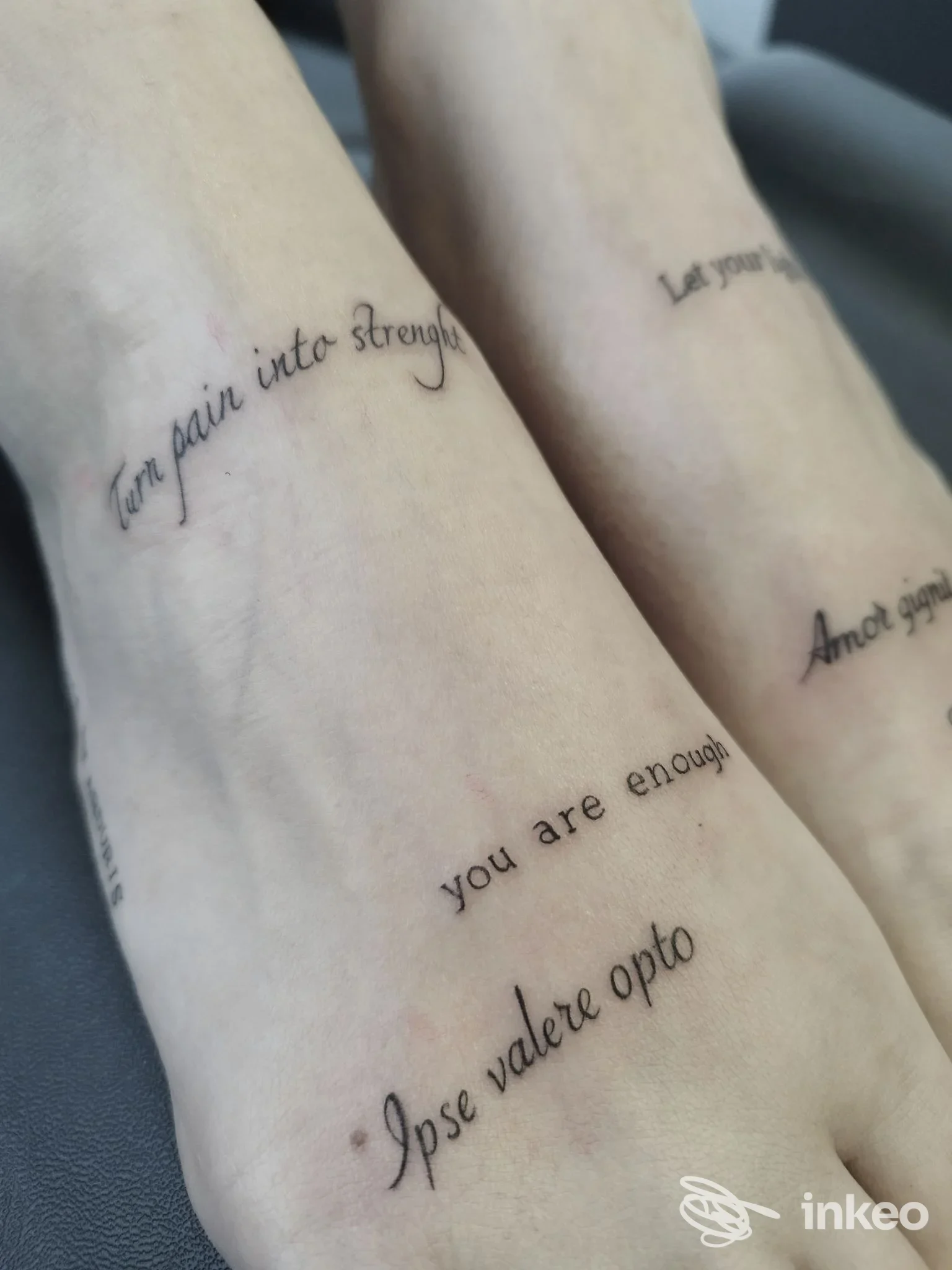 Due piedi con tatuaggi di testo su pelle chiara, tattoo visibile sulle dita e sul dorso, senza volto visibile e senza elementi di social media.