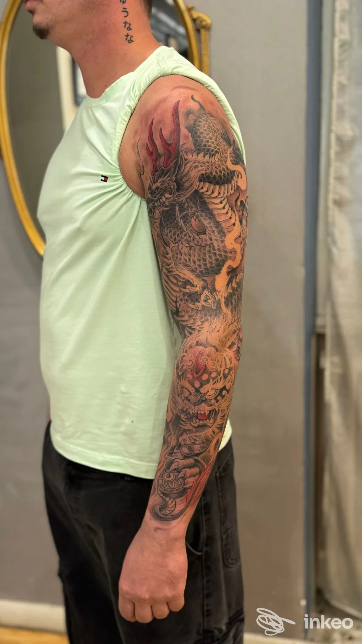 Braccio sinistro di un uomo con tatuaggio a manica ben visibile, visto lateralmente in studio, senza volto intero visibile.