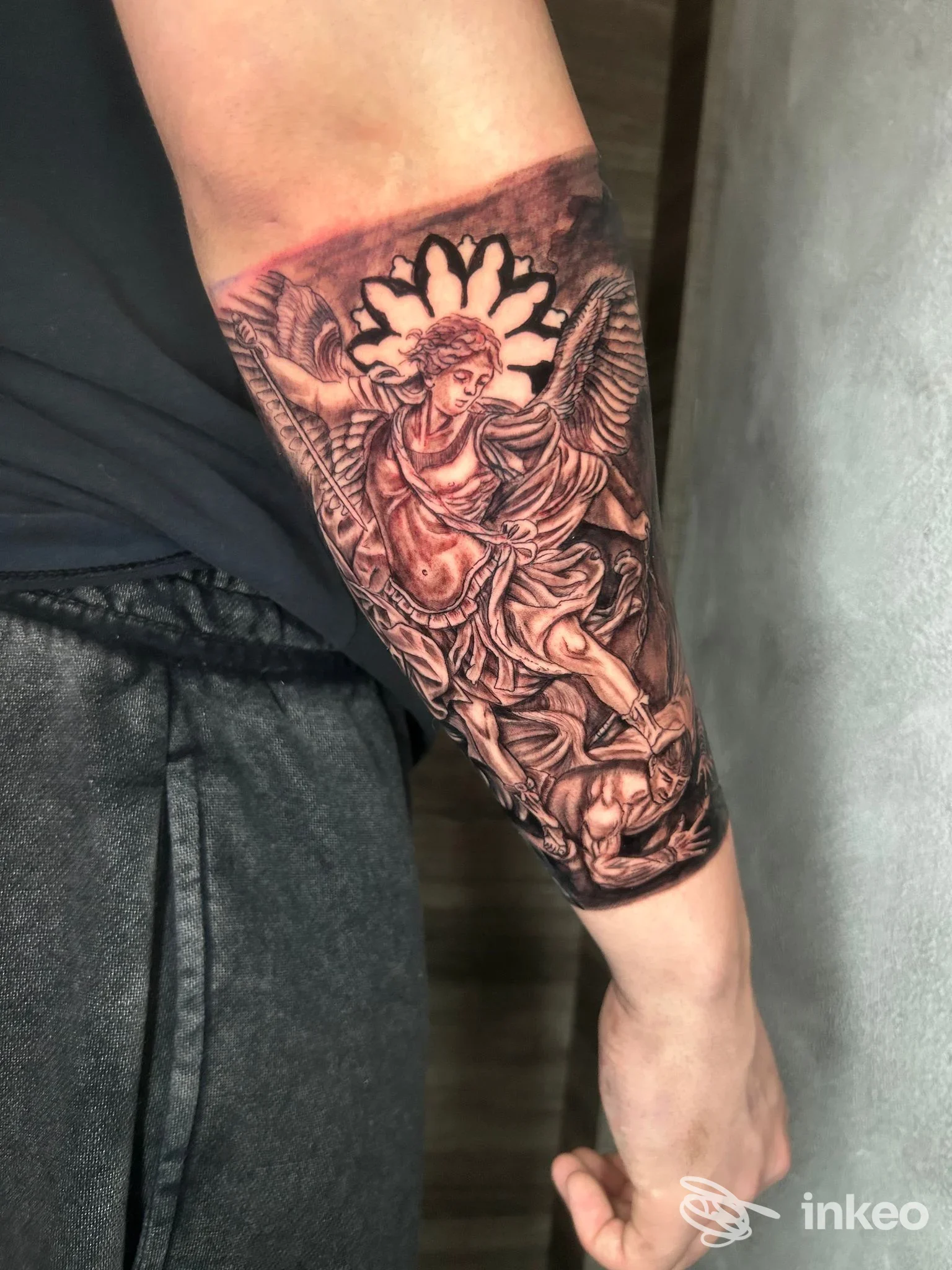 Tatuaggio realistico in bianco e nero sull’avambraccio, figura angelica con ali, occupa gran parte dell’avambraccio sinistro, stile dettagliato, senza testo o watermark visibile, eseguito dallo studio Carlo Corsi.