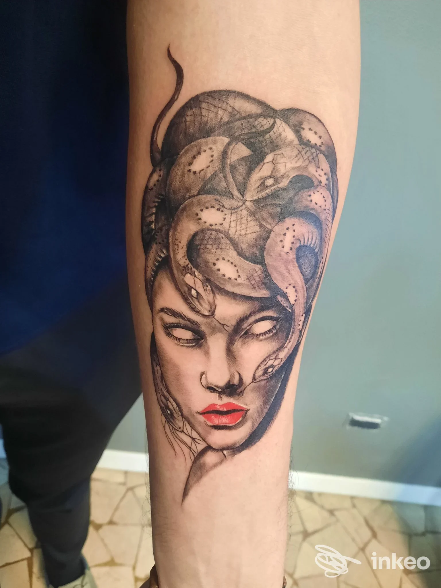 Tatuaggio sul braccio raffigurante una testa femminile in bianco e nero con capelli intrecciati, labbra rosse ben definite.