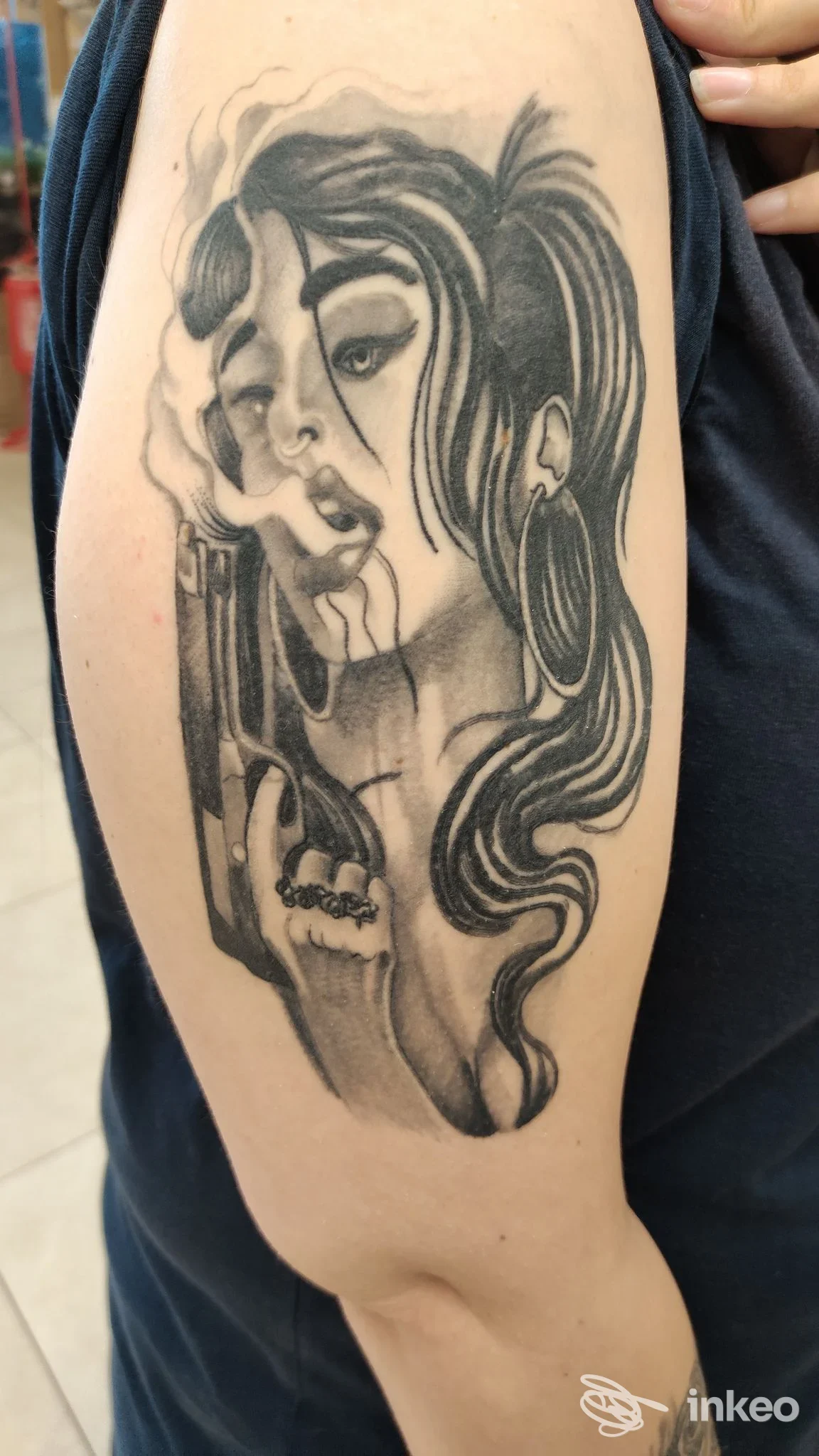 Tattoo sul braccio raffigurante una donna in bianco e nero, con capelli fluenti e sigaretta tra le dita, realizzata sulla pelle.