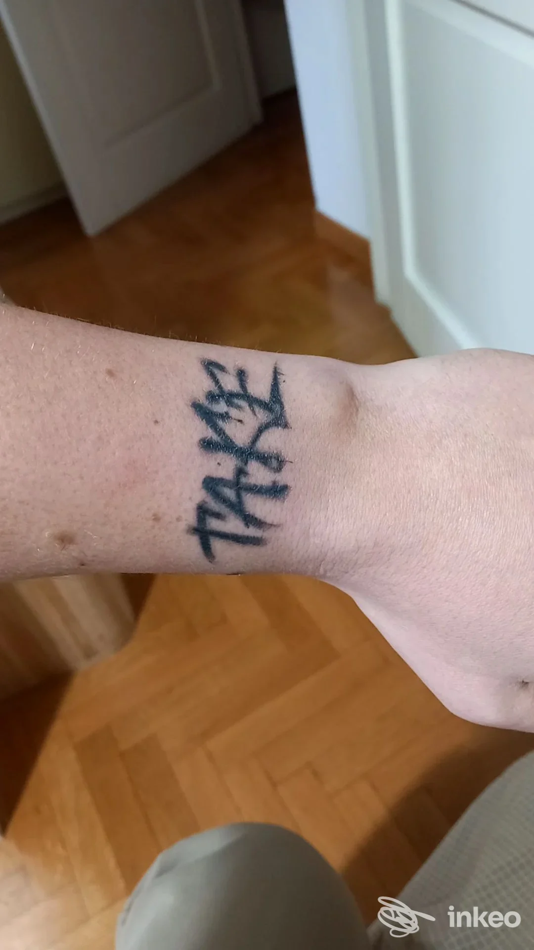 Polso visibile con tatuaggio nero: la parola 'THANKS' scritta verticalmente sul dorso del polso.