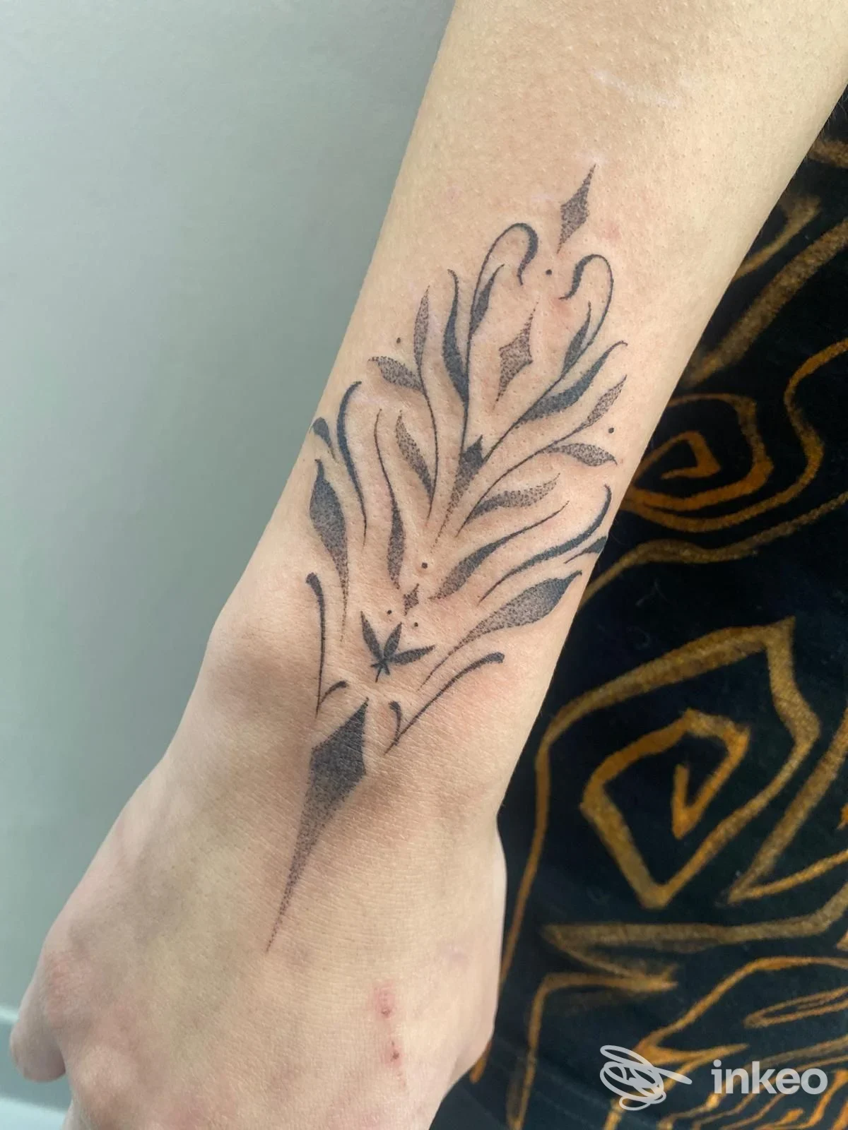 Tattoo floreale stilizzato sull'avambraccio, disegno nero su pelle chiara.