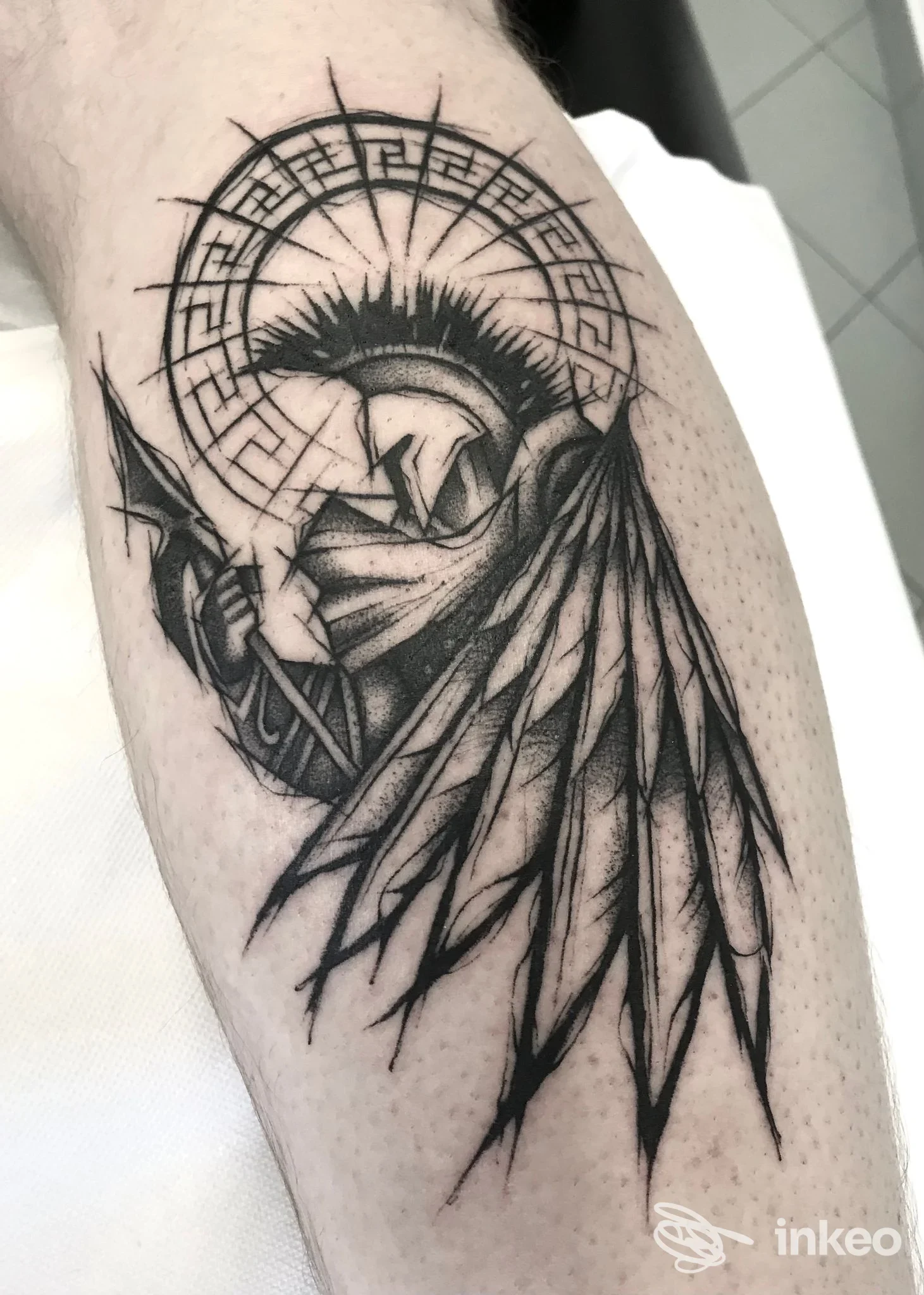 Tattoo a manica sull’avambraccio raffigurante un angelo con ali nette e halo circolare geometrico, eseguito in stile linework in bianco e nero; nessun testo o cornice visiva nei dintorni.