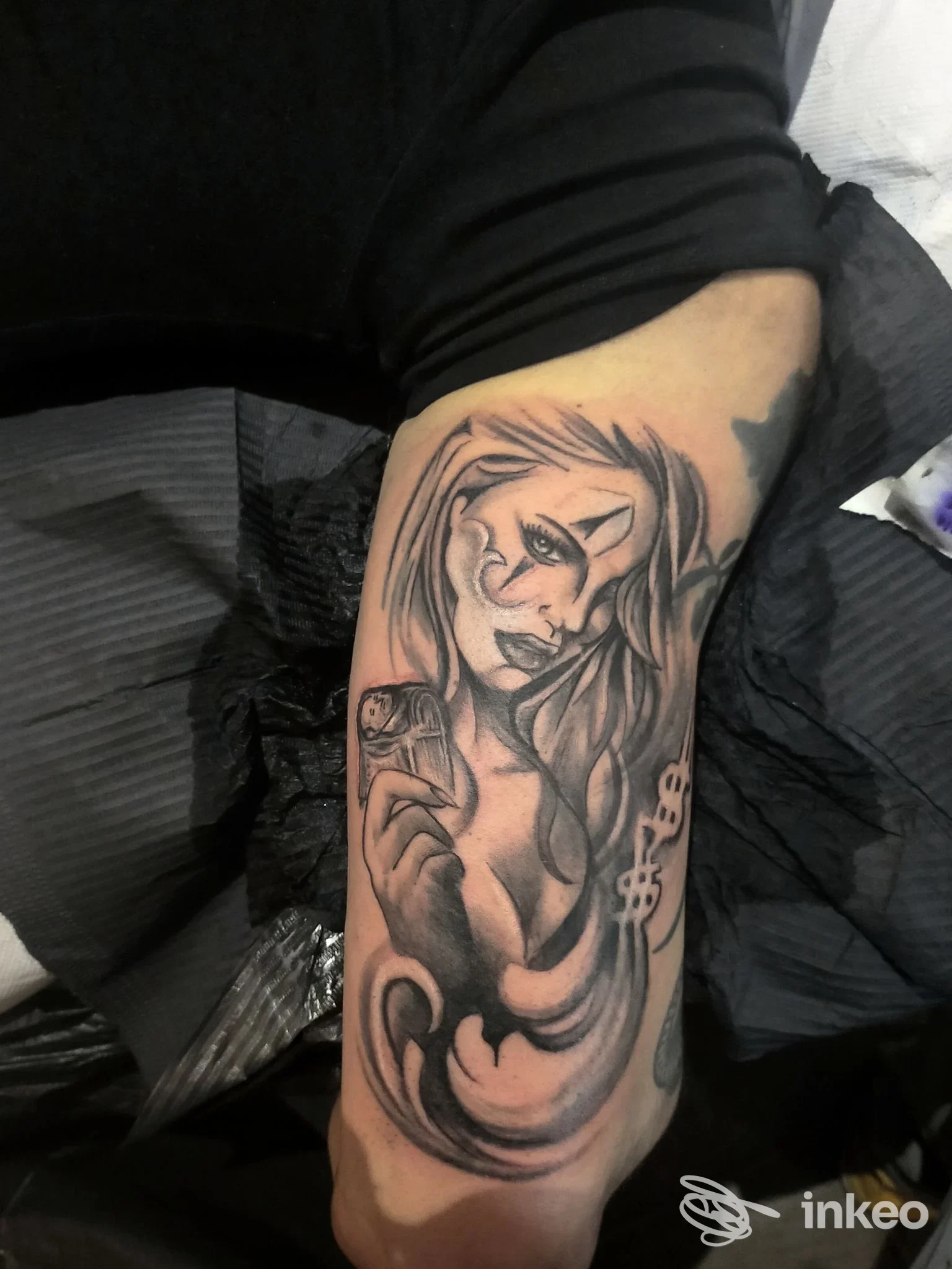 Tattoo grayscale su avambraccio raffigurante figura maschile, stile linework su pelle; nessun volto intero visibile.