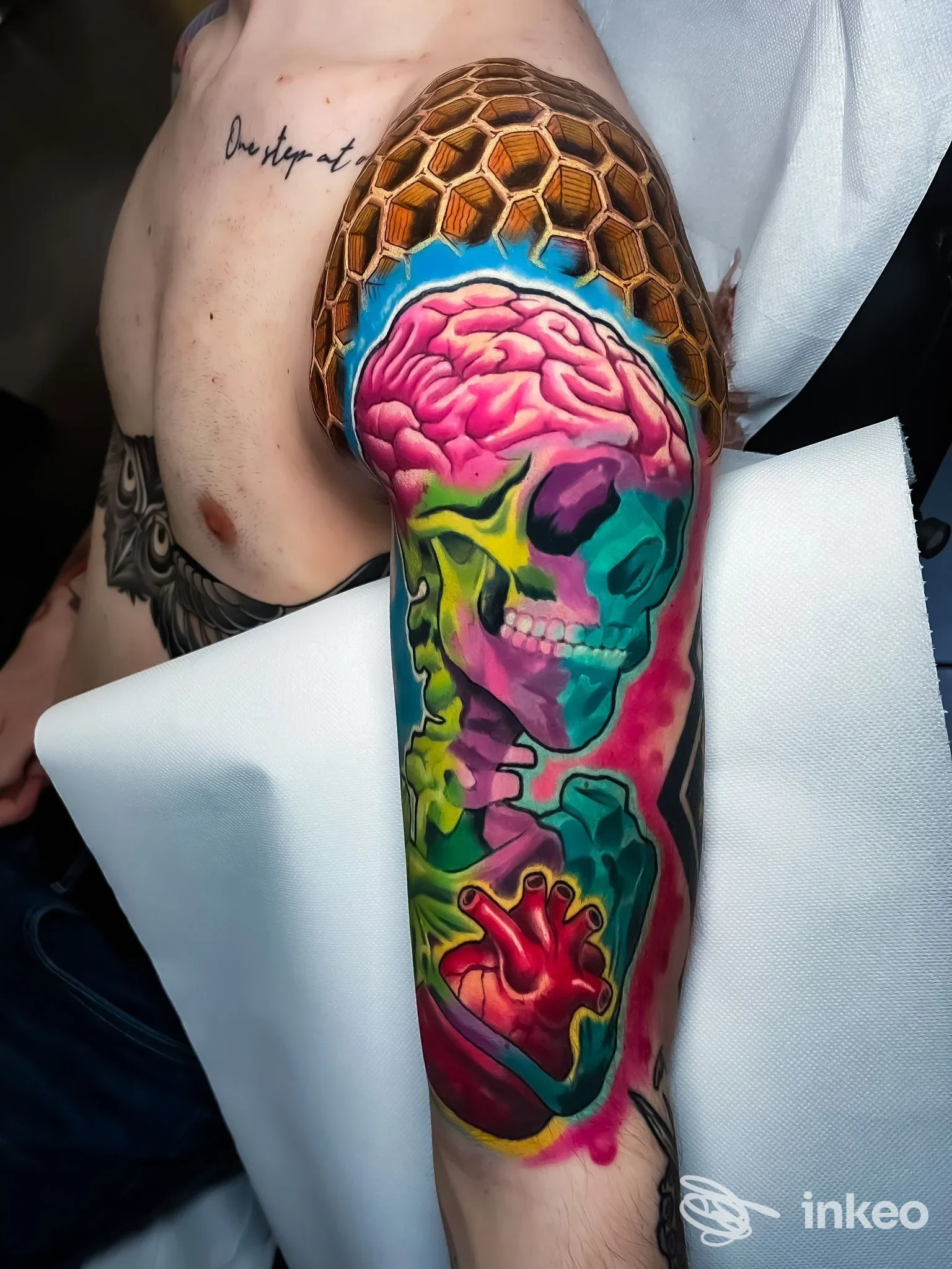 Tattoo colorato sull'avambraccio raffigurante un teschio e un cervello, con colori vivaci e dettaglio, eseguito su pelle reale, scatto in studio.