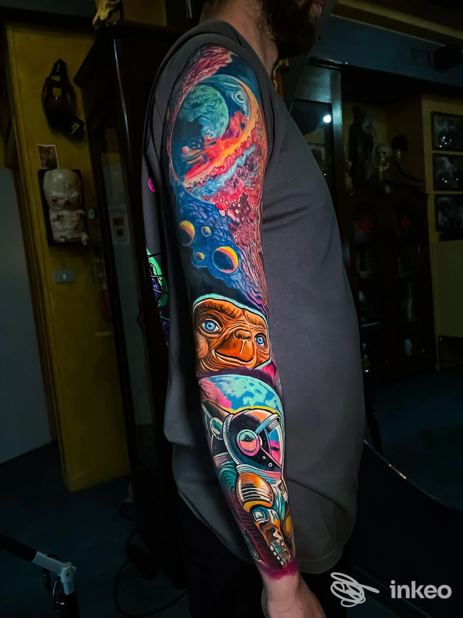 Braccio sinistro di un uomo con un tatuaggio colorato a tema spaziale, in uno studio chiamato Hive Tattoo Art Gallery.