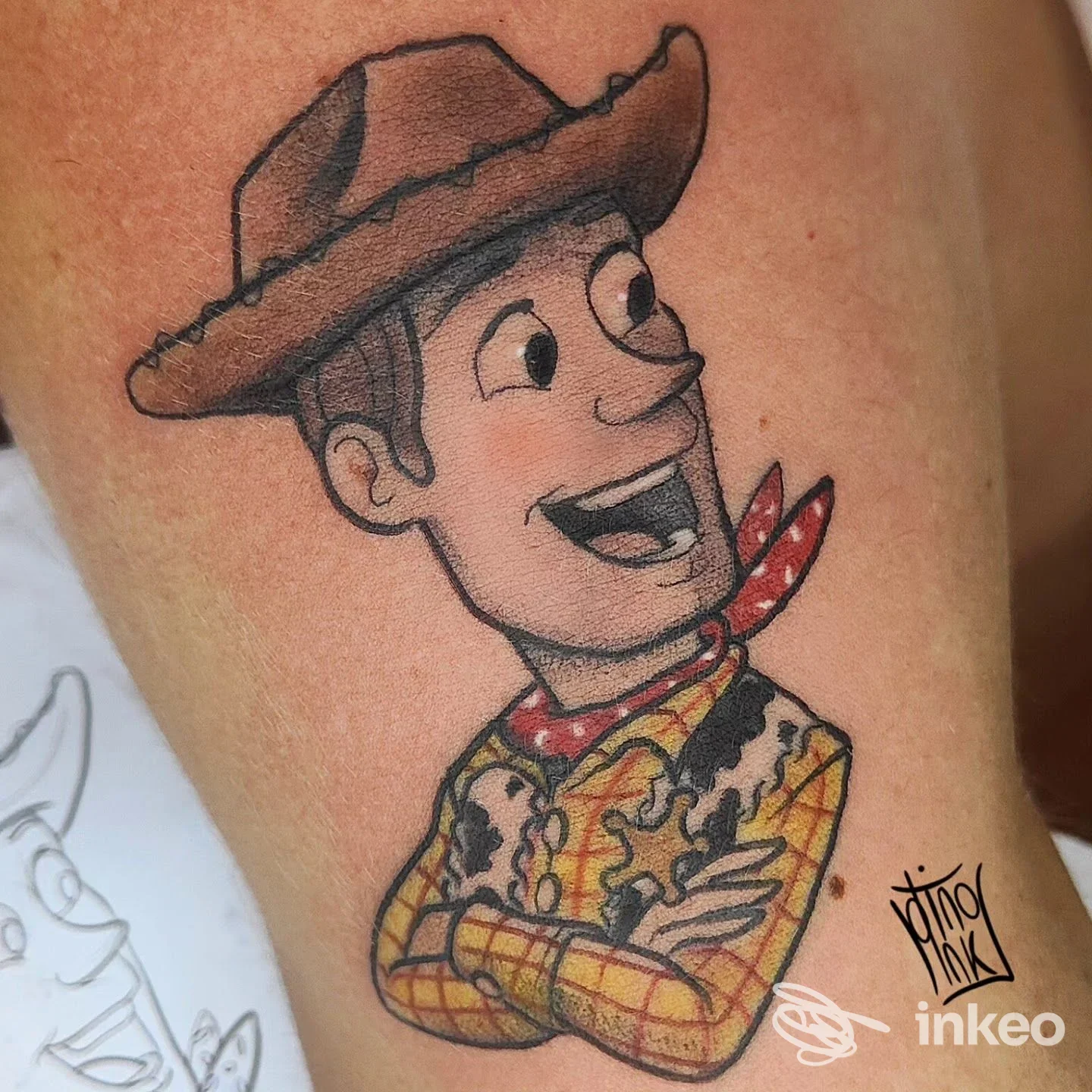 Tatuaggio reale su pelle raffigurante Woody di Toy Story sul braccio, disegno colorato e definito.