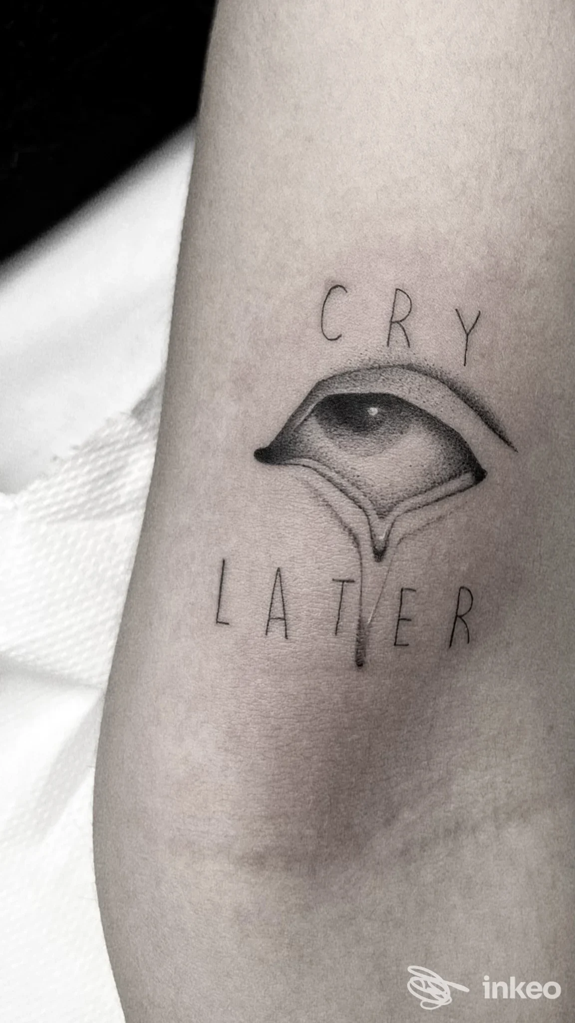 Tattoo sull'avambraccio raffigurante un occhio stilizzato con le parole 'CRY LATER' sopra e sotto. Studio: The Unofficial Tattoo Shop.