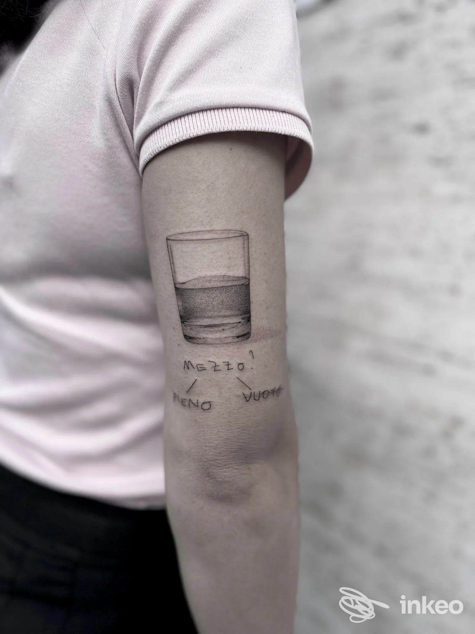 Tatuaggio sull'avambraccio raffigurante un bicchiere con liquido in due livelli, contorni netti e tratto nero su pelle chiara.