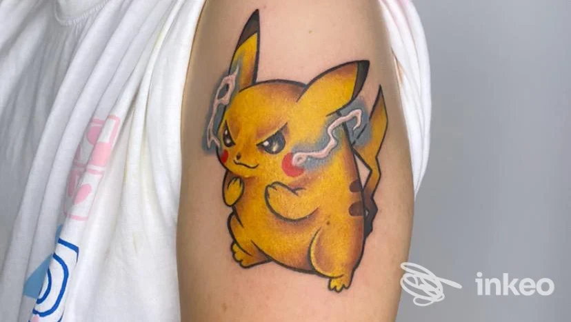 Tattoo Pikachu giallo sull'avambraccio di una persona, eseguito da SG Studio, sfondo neutro.