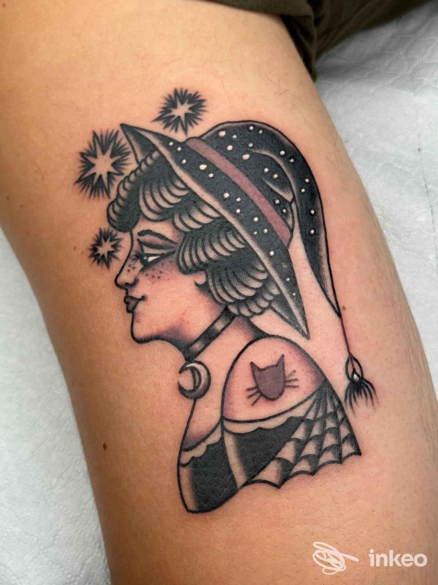 Tatuaggio in bianco e nero su braccio: profilo di una donna con cappello vintage, stile tradizionale, con dettagli di stelle e decorazioni.