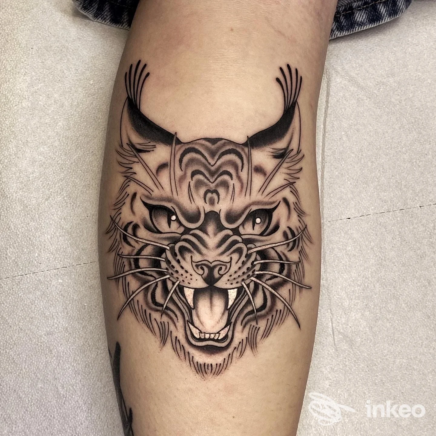 Tattoo realistica di una testa di gatto arrabbiato sulla gamba, con linework nero e sfumature, eseguito da LiberArte Tattoo.