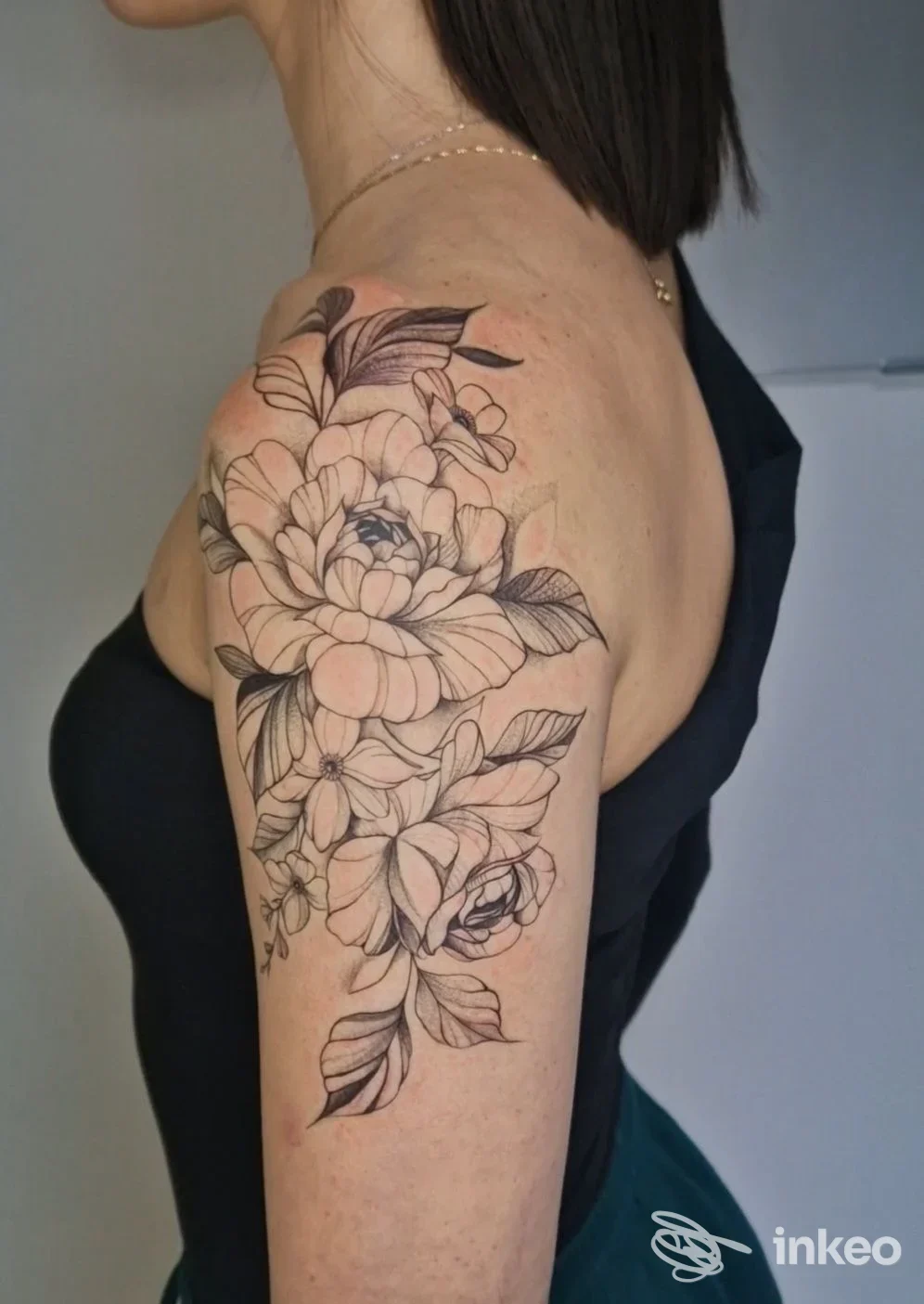 Tattoo floreale evidenziato sulla spalla e sul braccio sinistro, disegno a linee nere con sfumature, realizzato su pelle. Studio FineArt Tattoo.