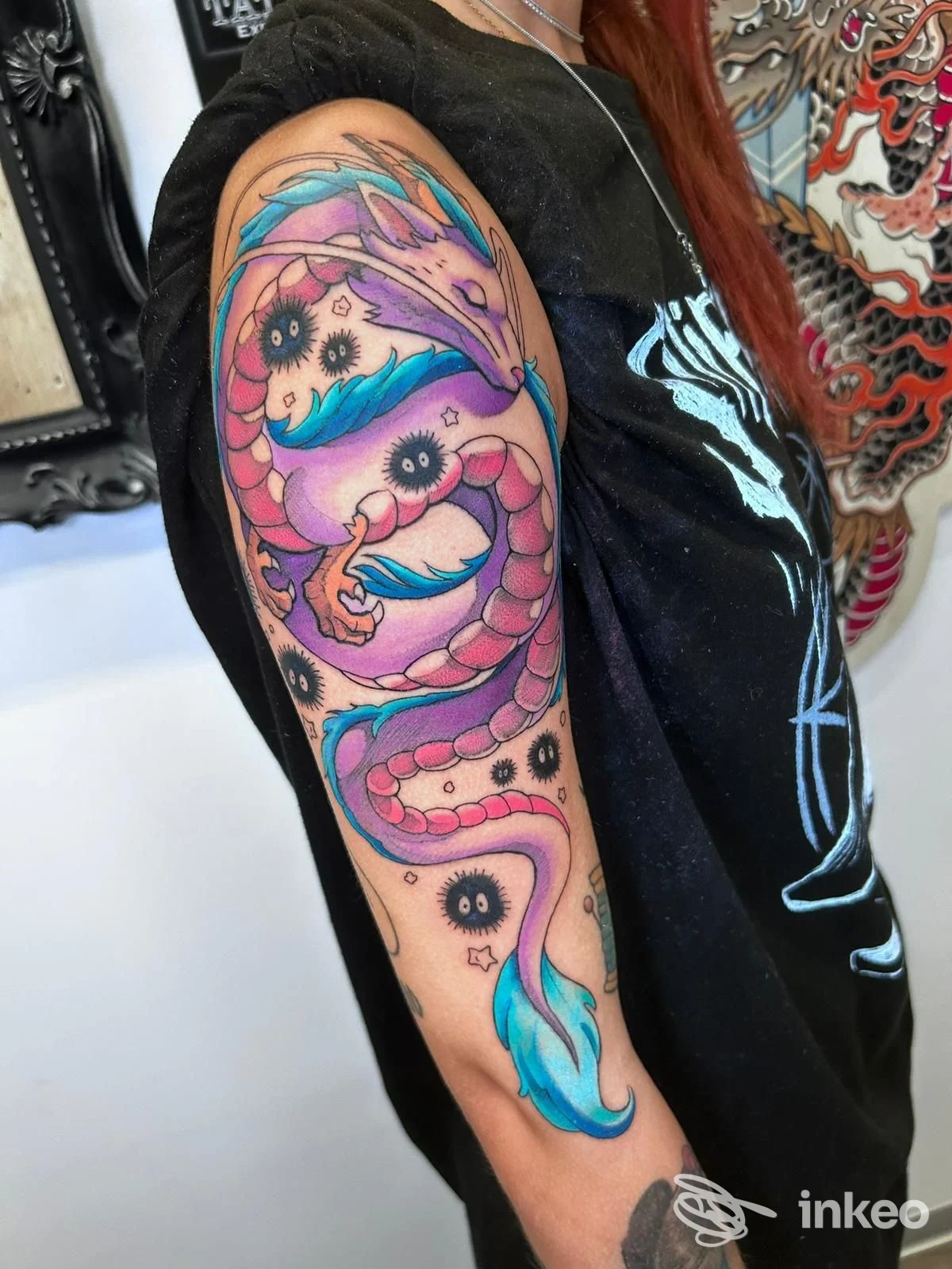Braccio sinistro di una persona con tatuaggio a serpente rosa e coda azzurra che avvolge l’avambraccio, sfondo con altri tattoo nello studio Ollink Tattoo