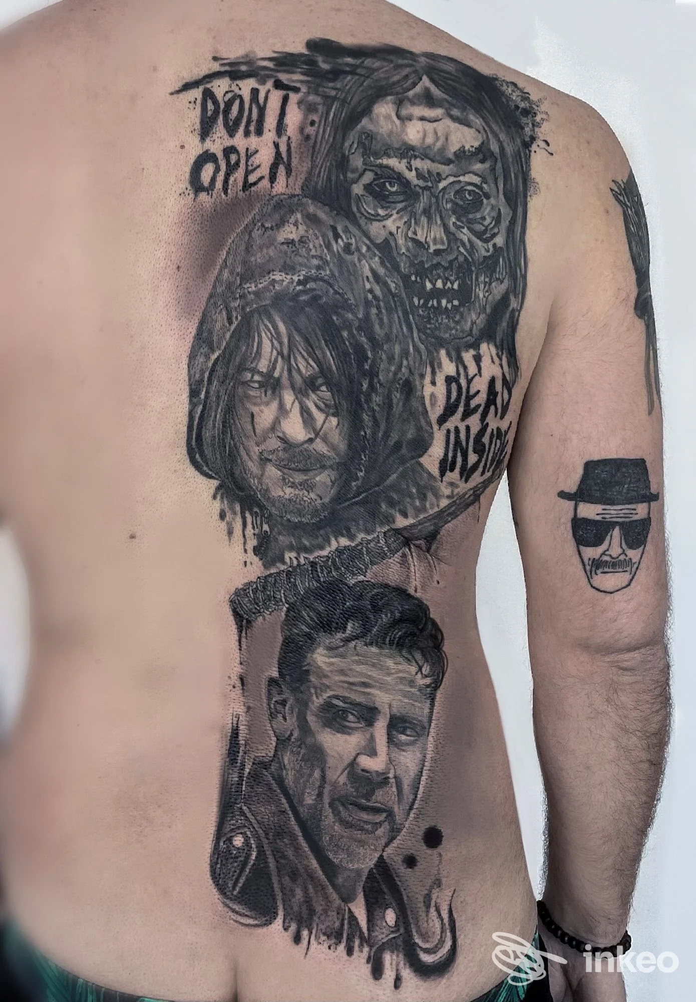 Schiena di una persona con vari tatuaggi in bianco e nero, ritratti realistici e motivi, visibili chiaramente su pelle. Studio Kuno Ink.