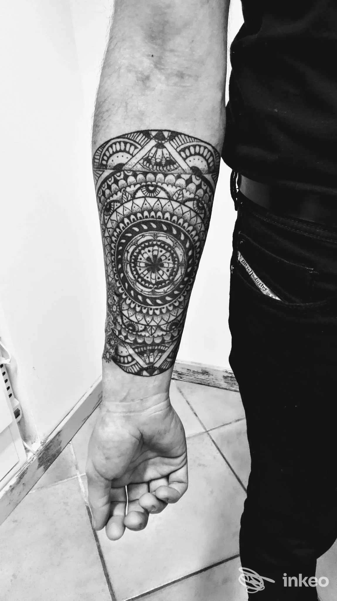 Tattoo geometrico mandala sul braccio, stile blackwork, visibile una porzione dell’avambraccio e della mano, senza volto visibile.
