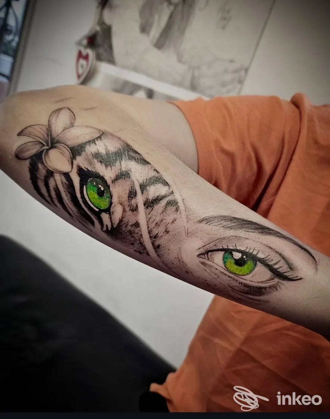 Tatuaggio realista su avambraccio: occhi verdi di felino e fiore, privo di testo o watermark visibile, eseguito su pelle.