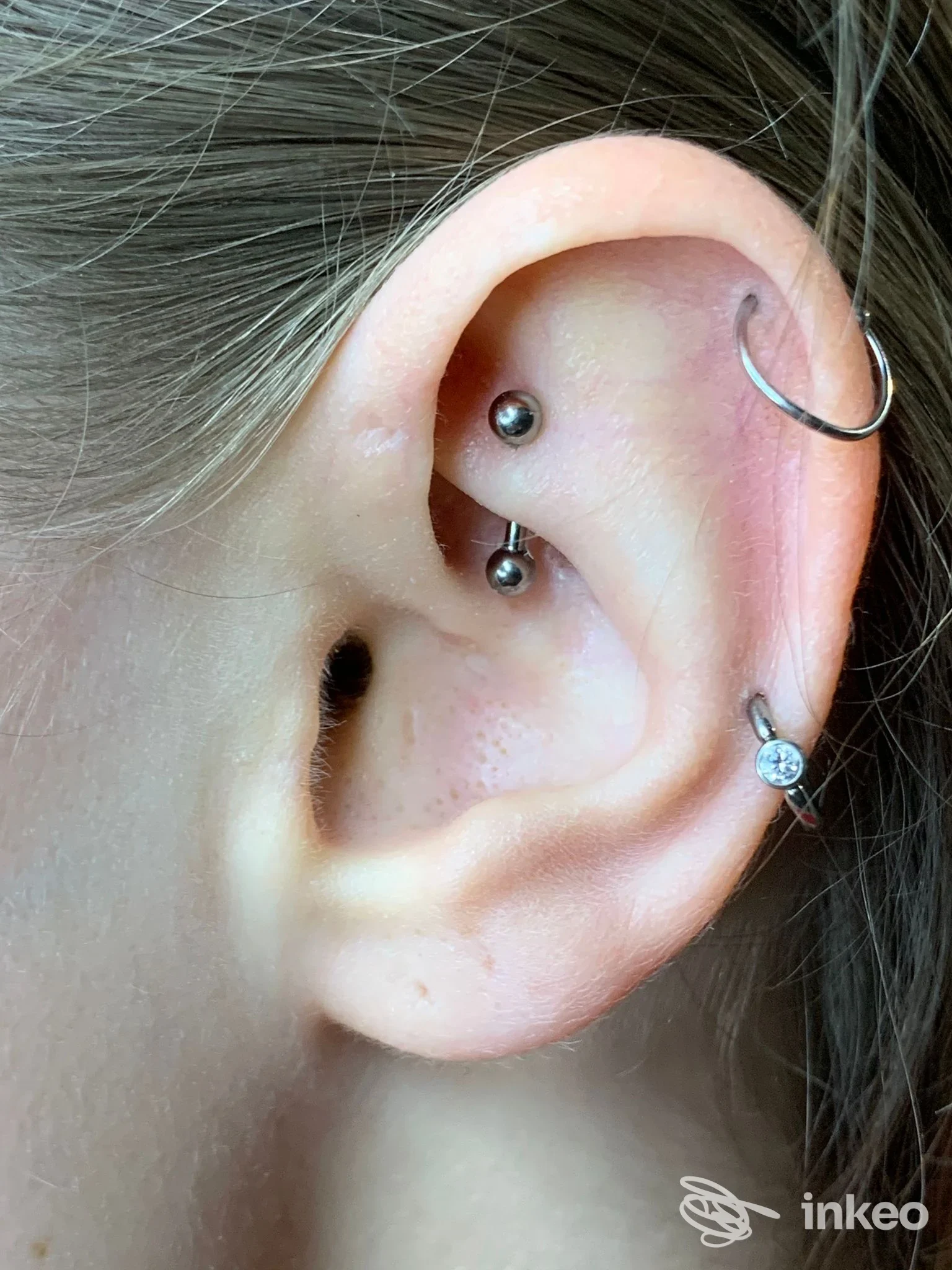 Piercing multipli all'orecchio in primo piano con gioielli su pelle reale; senza testo o watermark visibile, scatto singolo.