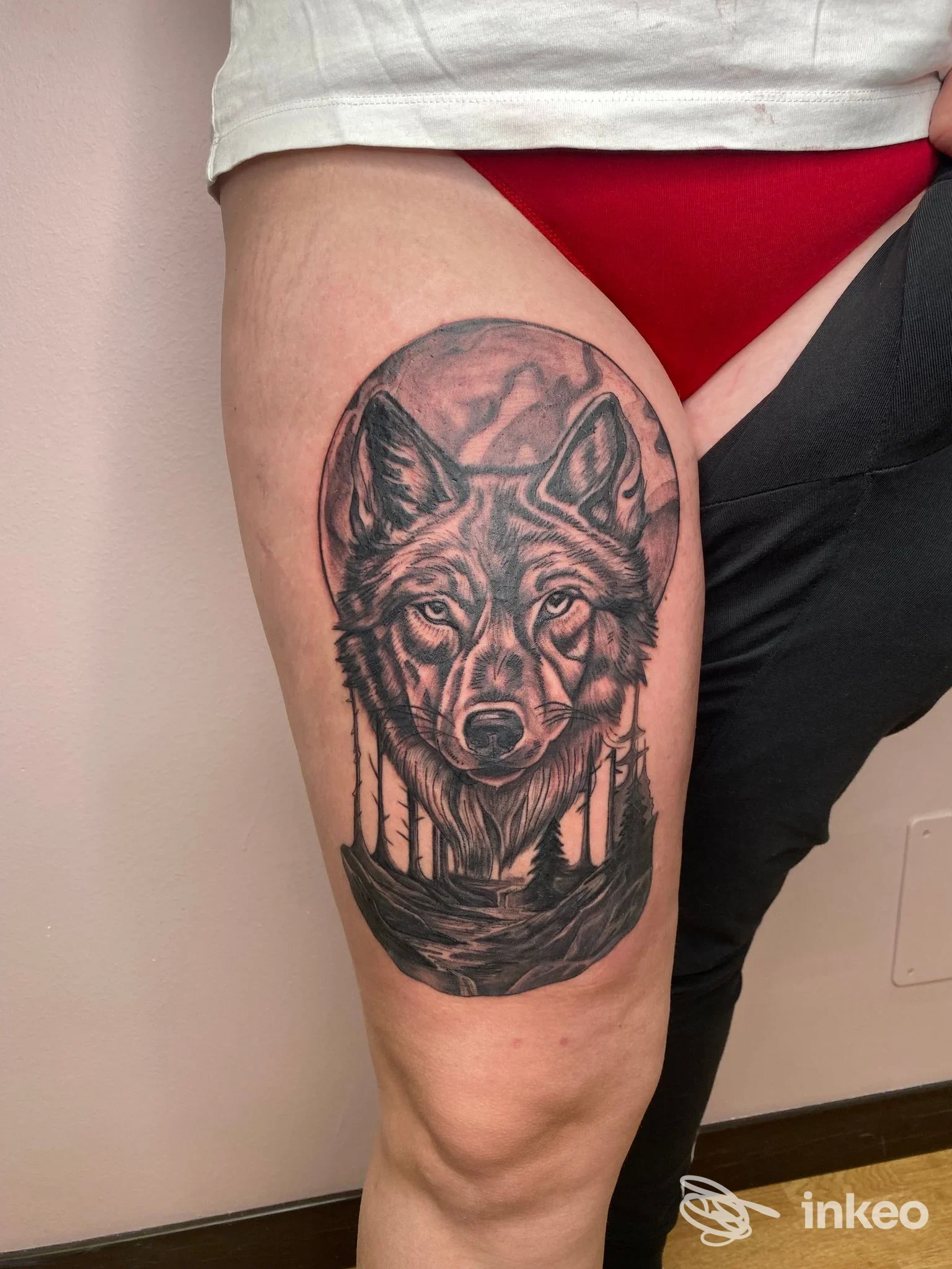 Tattoo sul polpaccio raffigurante un lupo stilizzato in tonalità nere e grigie, realisticamente definito, visibile sulla pelle senza elementi di interfaccia sociale.